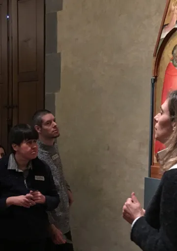 gruppo di persone ascolta una guida museale di fronte a un dipinto