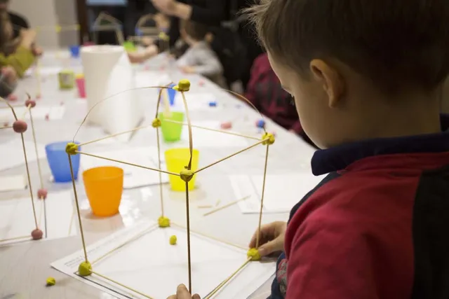 Bambini attorno a un tavolo durante un laboratorio creativo con costruzioni geometriche