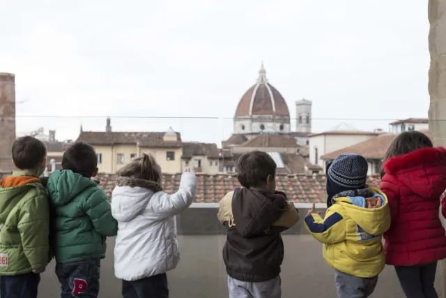 Bambini di spalle affacciati dalla terrazza panoramica del Verone in direzione del Duomo