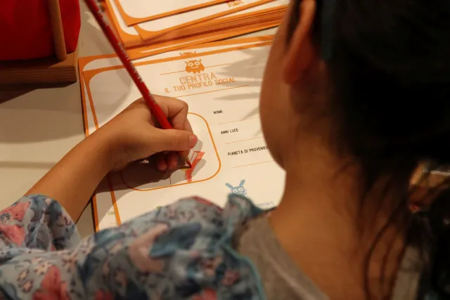 Bambina seduta, vista di spalle, che disegna