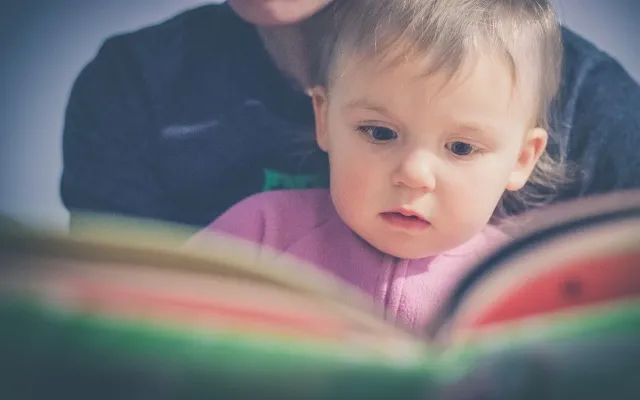 bambina che guarda le illustrazioni di un libro insieme alla madre