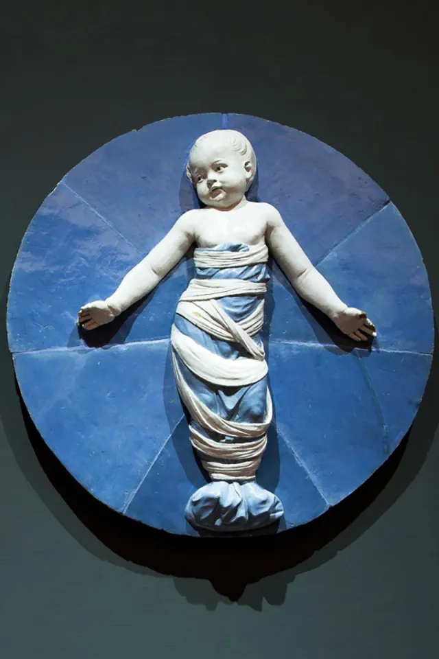 tondo in terracotta invetriata raffigurante Putto in fasce 