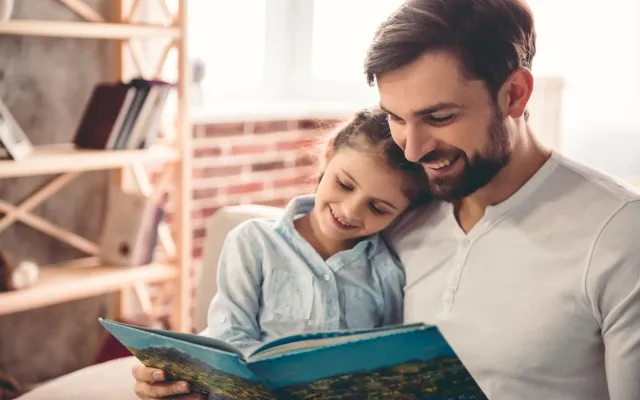 padre che legge un libro con la figlia per evocare il tema dell'affido al centro della Presentazione indirizzi operativi per l'affidamento familiare