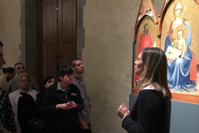 gruppo di persone ascolta una guida museale di fronte a un dipinto