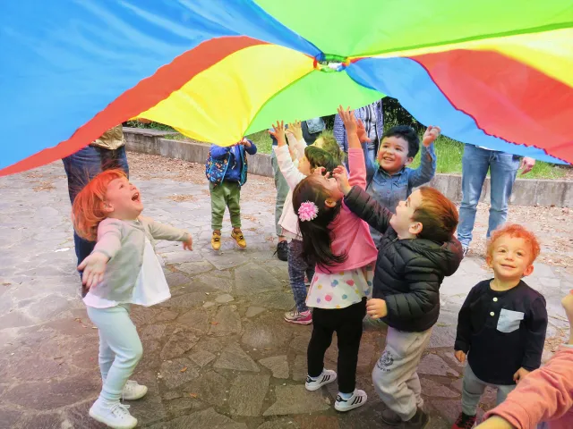 Bambini ridenti in piedi all'ombra di un aquilone colorato