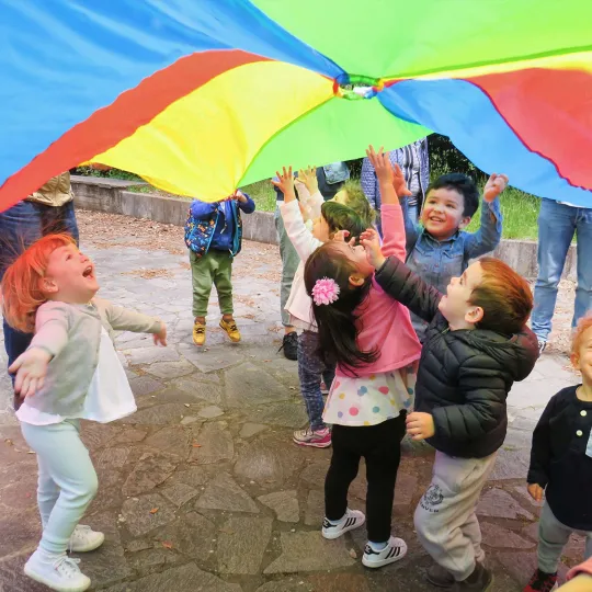 Bambini ridenti in piedi all'ombra di un aquilone colorato