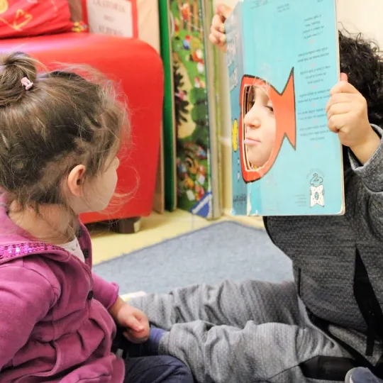 Due bambini giocano assieme seduti uno di fronte 