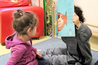 Due bambini giocano assieme seduti uno di fronte 