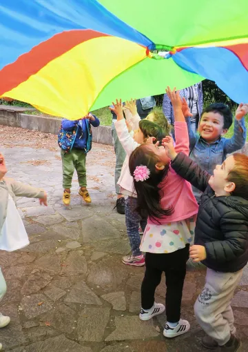 Bambini ridenti in piedi all'ombra di un aquilone colorato